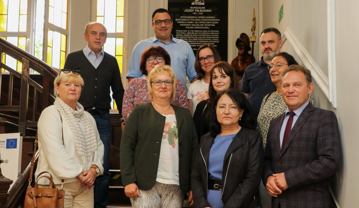 Grupa nauczycieli z wicestarostą we wspólnym zdjęciu na schodach w pszczyńskim starostwie.