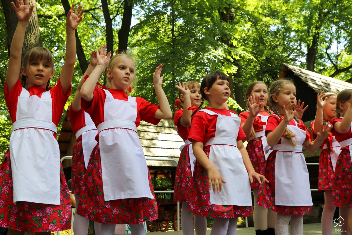 Dziewczynki występujące na scenie w czerwonych sukienkach.
