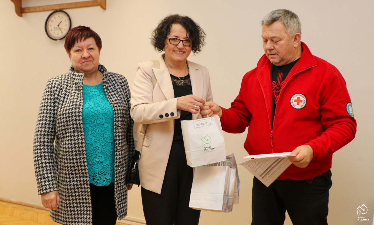Starosta Barbara Bandoła, szef klubu Marek Gruszka i kobieta na wspólnym zdjęciu. Starosta przekazuje torbę z logo powiatu ze słodyczami, kawą i gadżetami dla krwiodawców