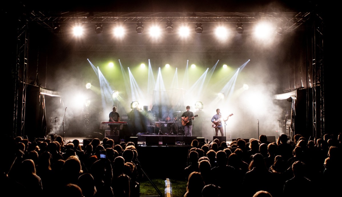 Scena podczas rockowego koncertu plenerowego, na scenie zespół, przed scena publiczność