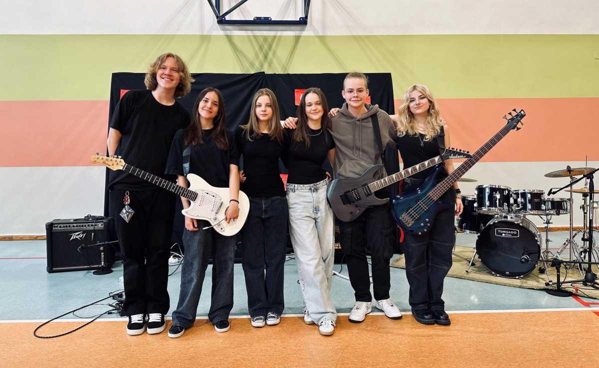 MKłodzi muzycy zespołu stoją na sali trzymają instrumenty