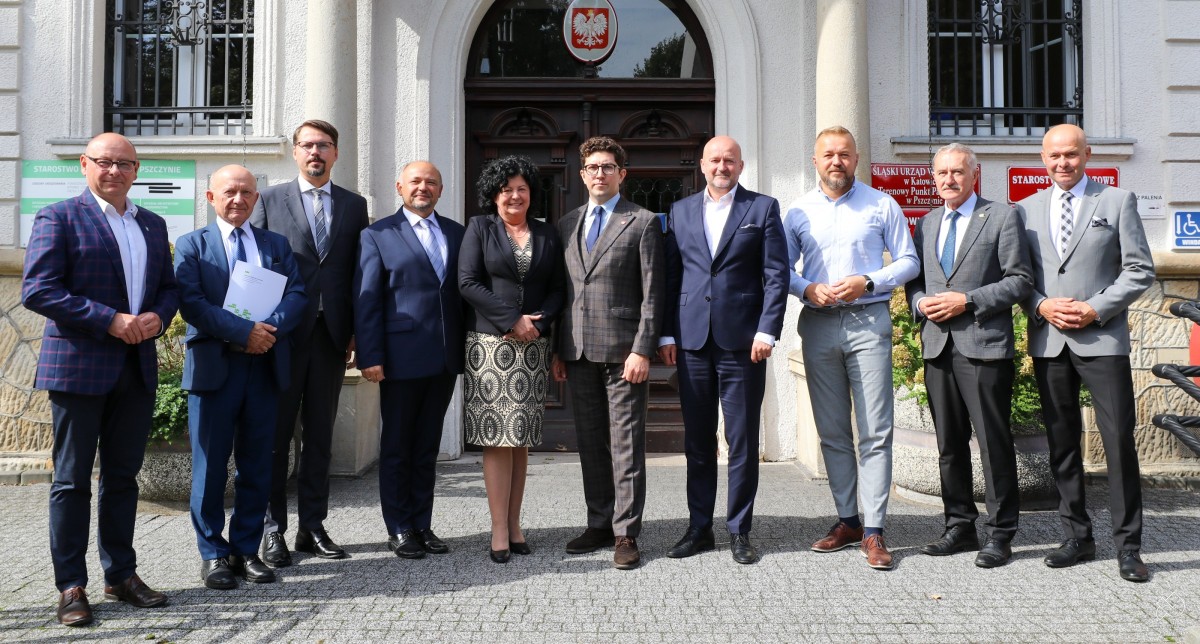 samorzadowcy oraz posłowie stoja obok siebie przed budynkiem starostwa.