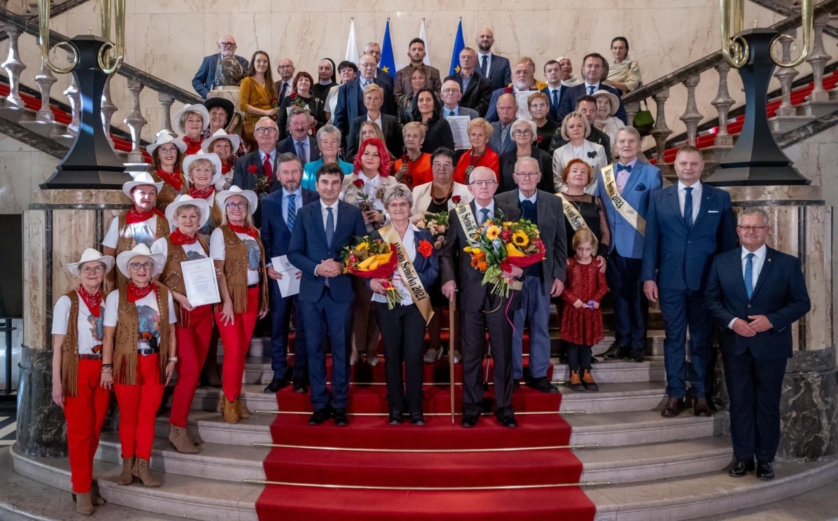 Wyróżnieni seniorzy na schodach razem z samorządowcami.