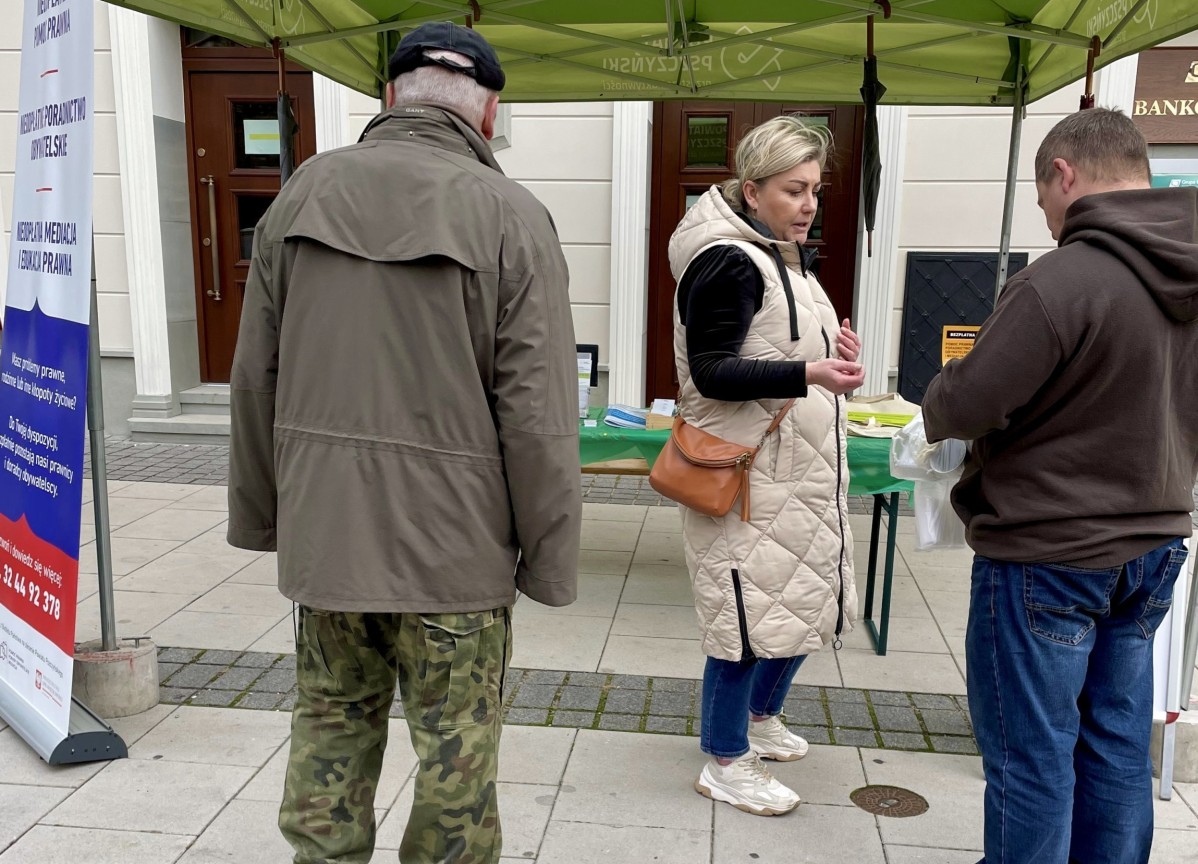 Kobieta rozdająca materiały promocyjne przechodniom na rynku.