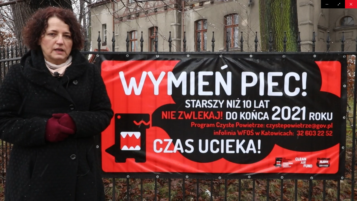 Starosta Barbara Bandoła stoi przed banerem informującym o konieczności wymiany starych pieców.